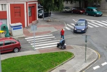 An intersection where someone is descending down an ADA-compliant ramp on the sidewalk